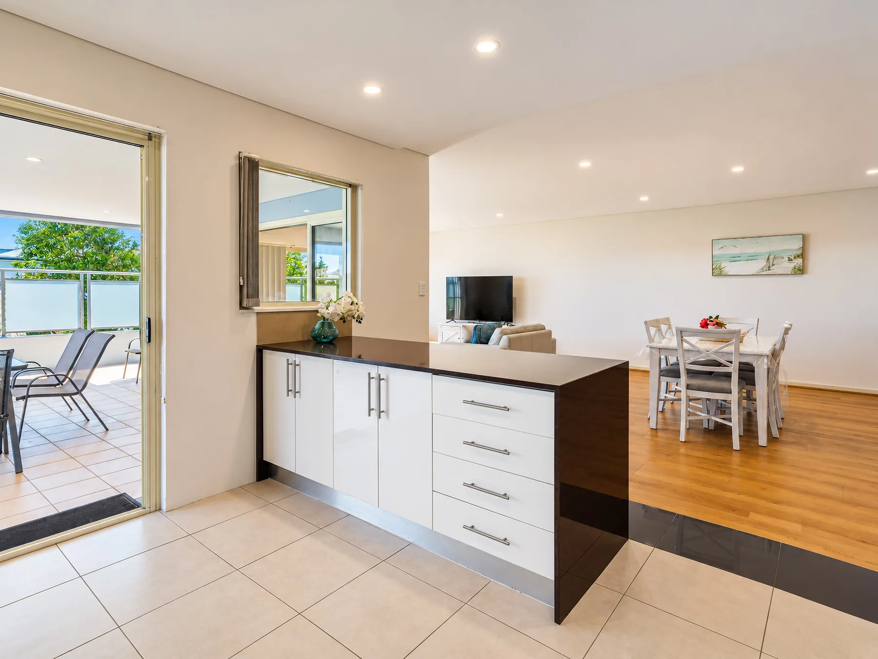 An open-plan kitchen and dining area, with a counter separating the tiled floor from wood flooring.