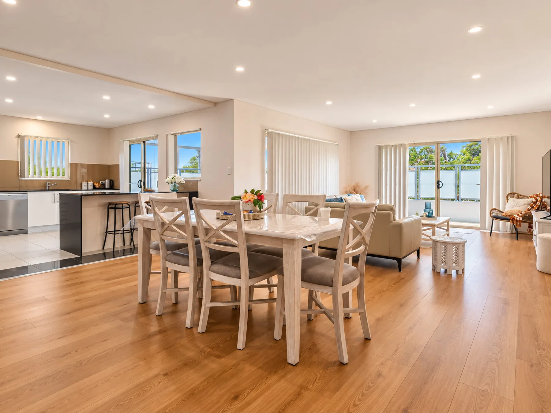 An open-plan living and dining area features a wooden dining table and kitchen.