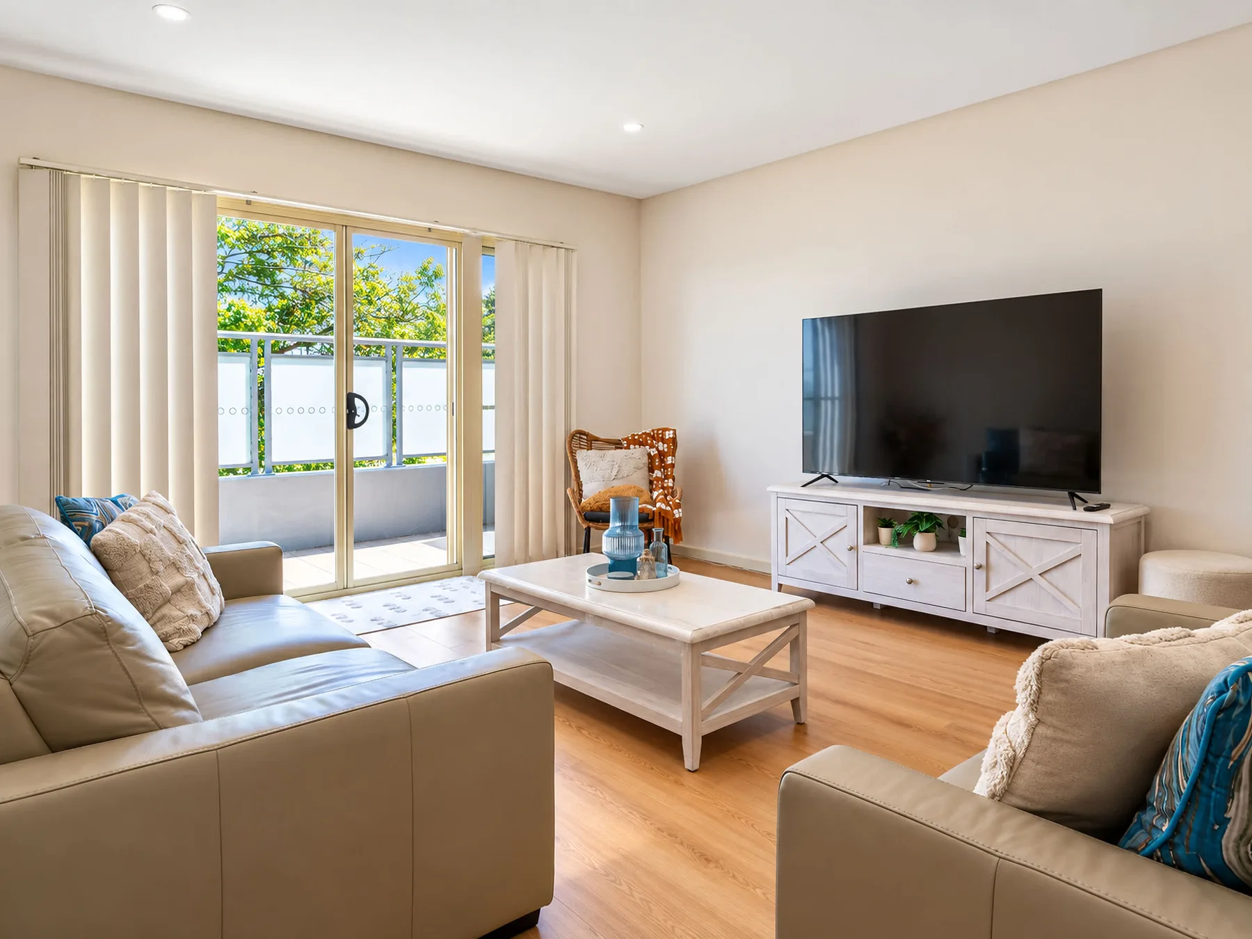A bright living room with seating, a coffee table, and a television.