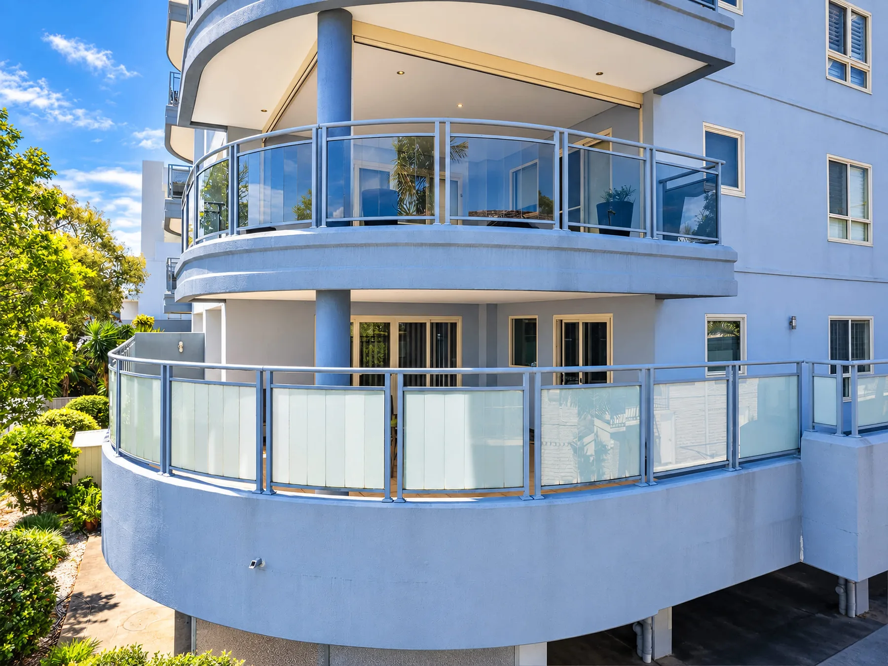 A modern apartment building with curved balconies and glass railings.