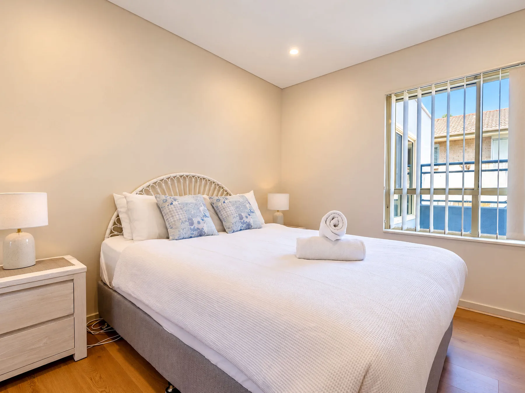 A bedroom with a neatly made bed beside a window.
