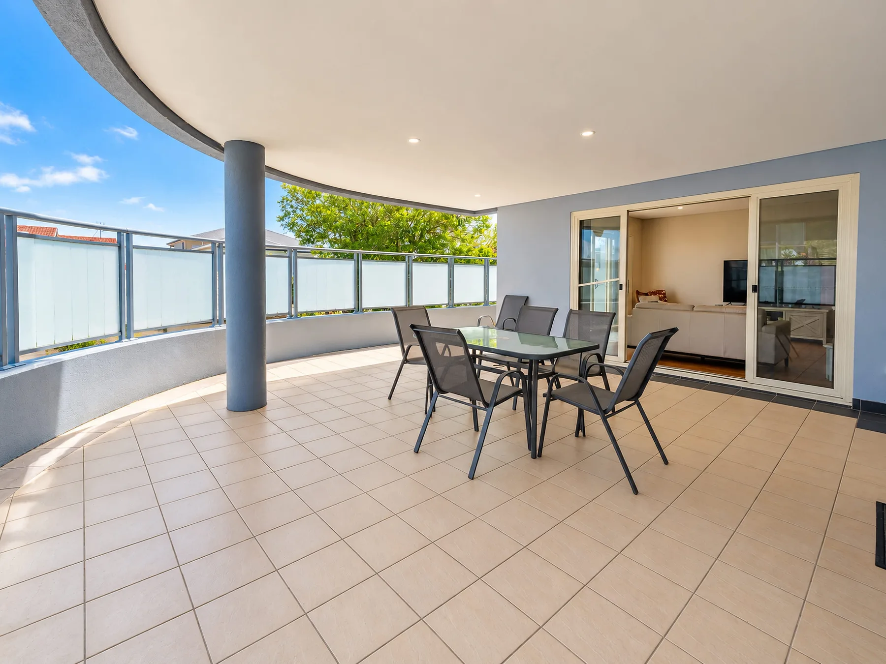 A spacious tiled terrace with outdoor seating and a view of the kitchen.