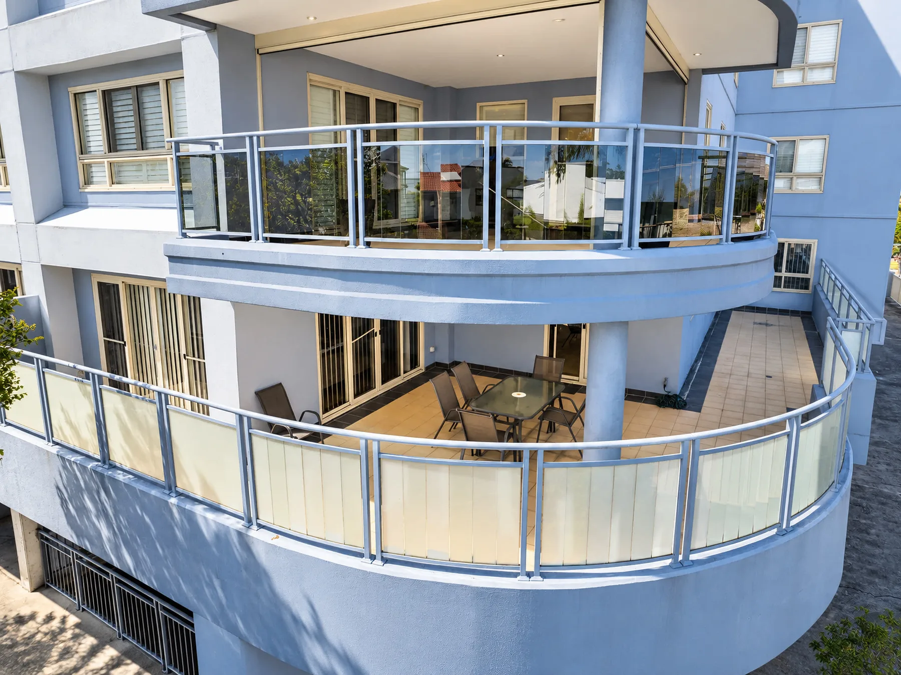 A blue apartment building with curved balconies and glass railings.