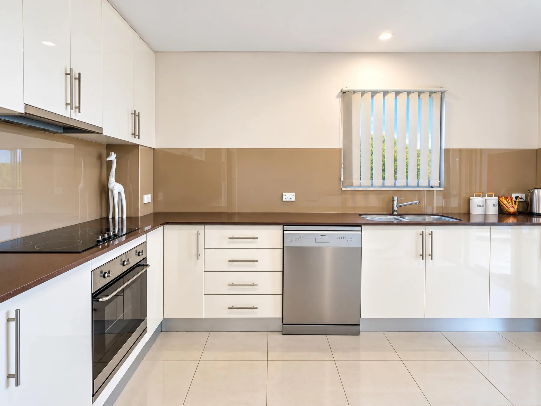 A bright kitchen with white cabinets, a countertop, and a window.