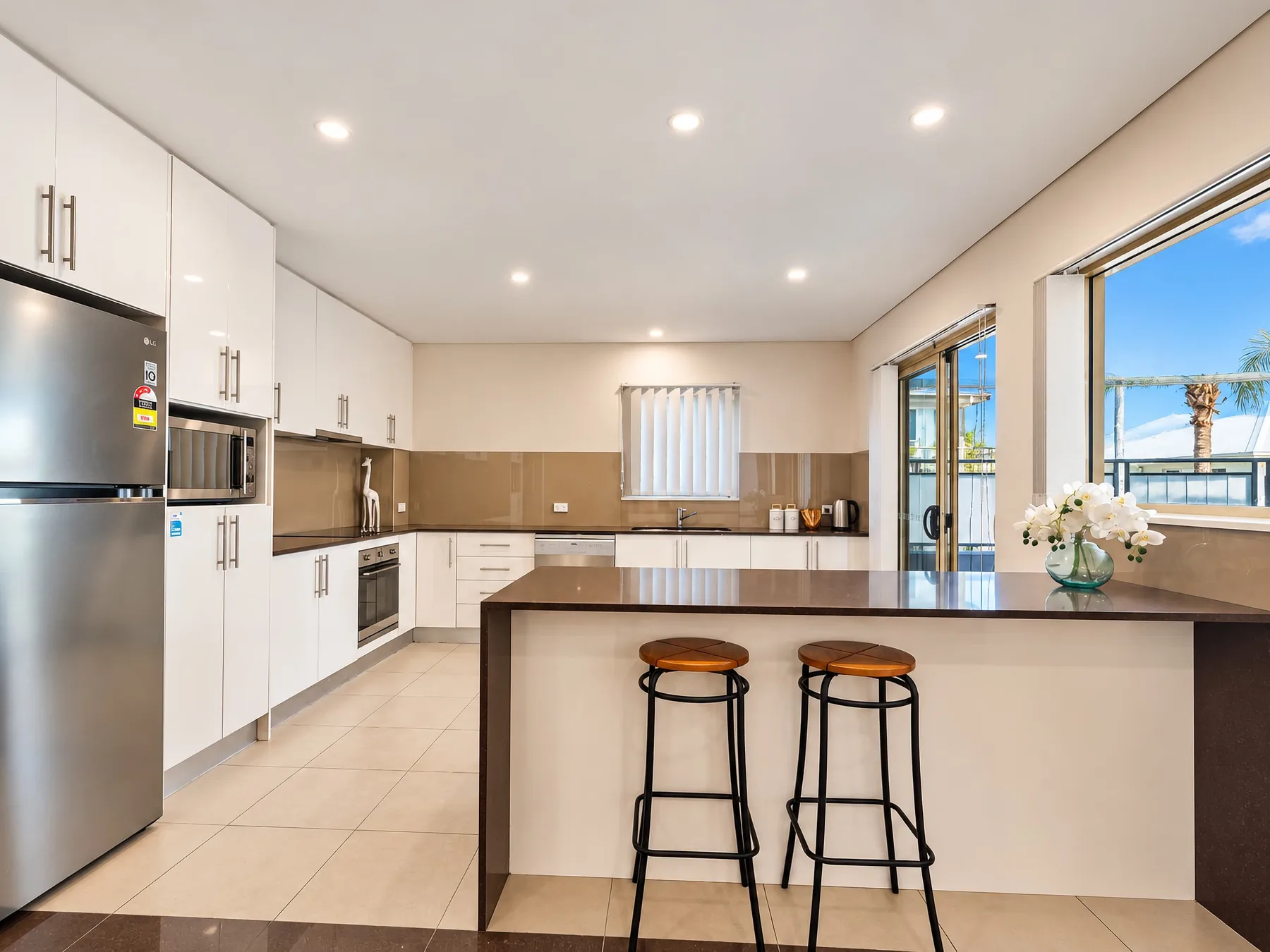 A bright kitchen with white cabinetry and a wide island with bar seating.