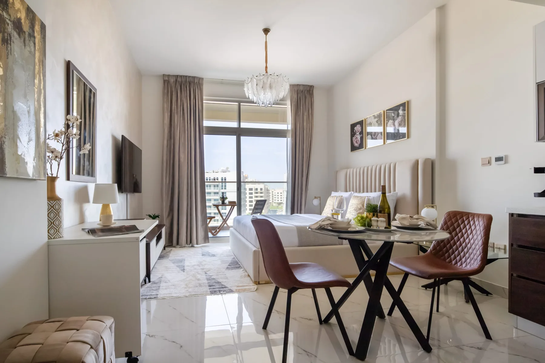 A bedroom with a bed and a small dining table beside the window.