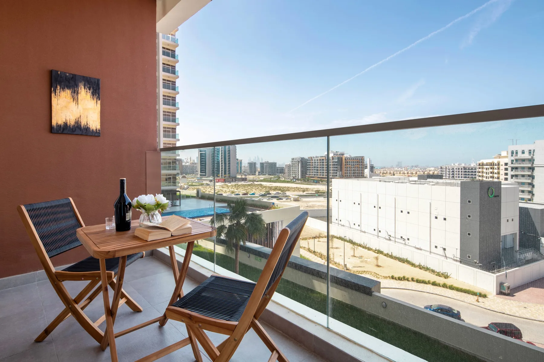 A balcony seating area overlooks nearby buildings beneath a clear sky.