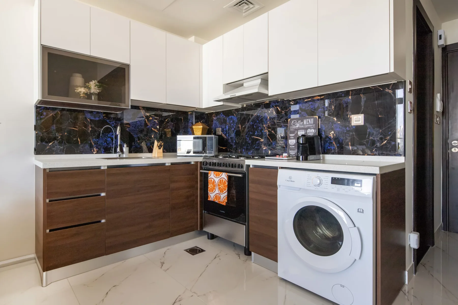 A modern kitchen with dark counters and a washing machine.