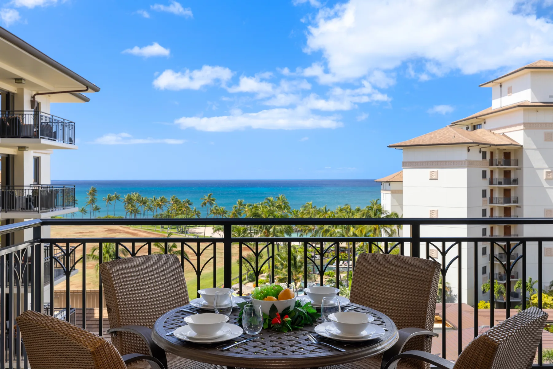 Una zona de comedor en un balcón da a palmeras y al mar.