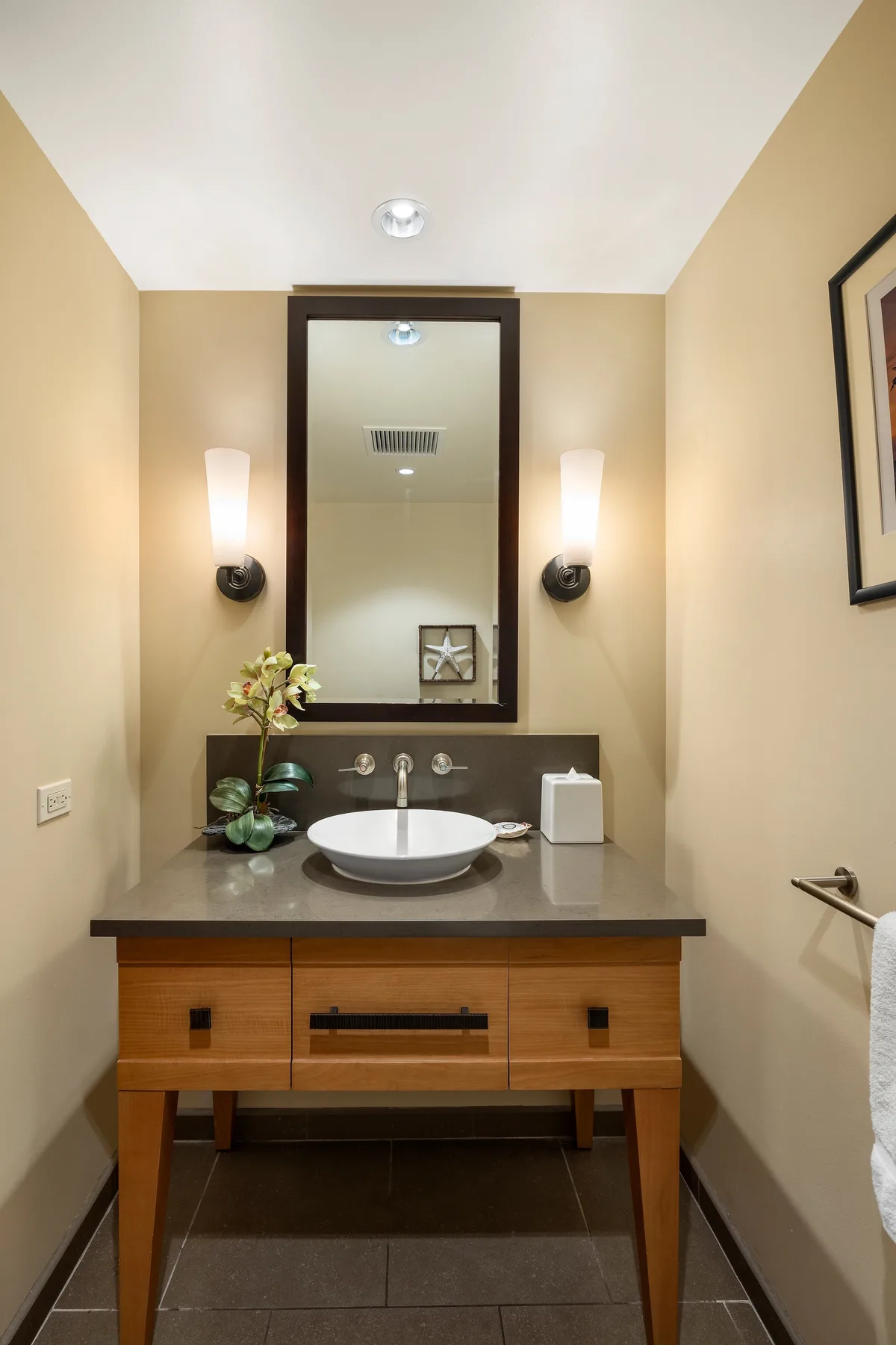 Un mueble de baño con lavabo redondo, espejo y luces de pared.