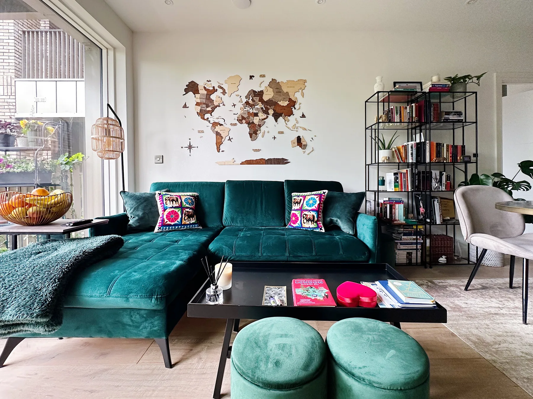 A living room with teal seating, a coffee table, and a world map on the wall.