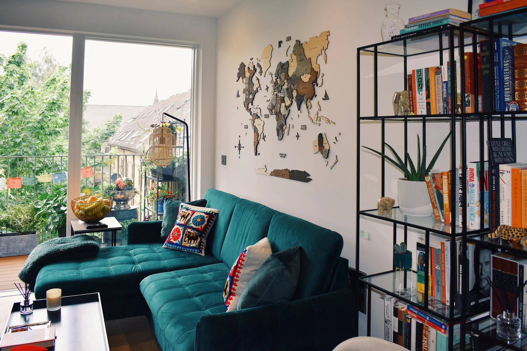 Living room with teal seating, a wall map, and a tall bookshelf.