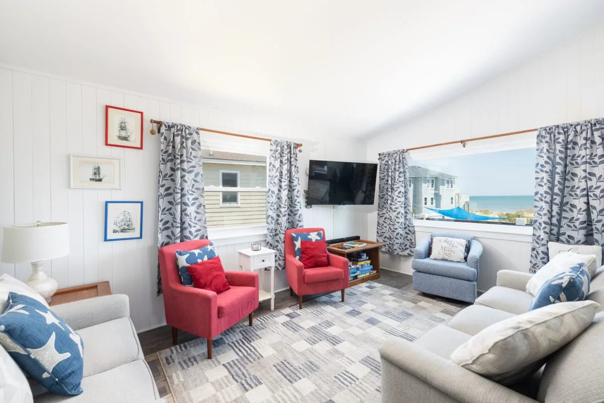 A bright living room with colorful seating and large windows overlooking the water.
