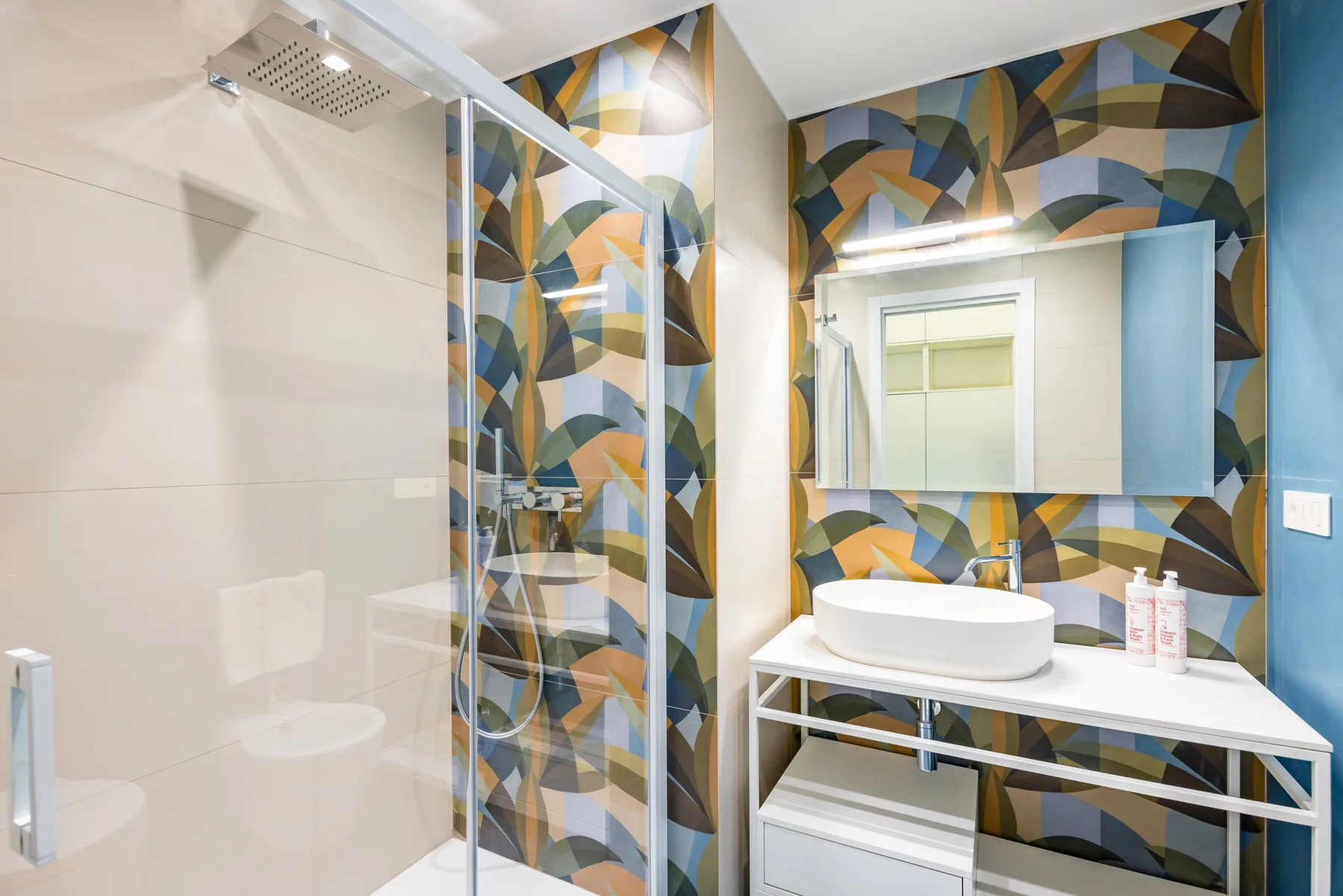 Un baño moderno con ducha de vidrio y un lavabo bajo un espejo grande.