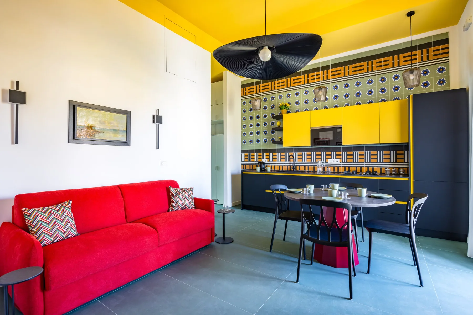 Una luminosa sala de estar y comedor tiene asientos rojos y una mesa bajo un techo amarillo.