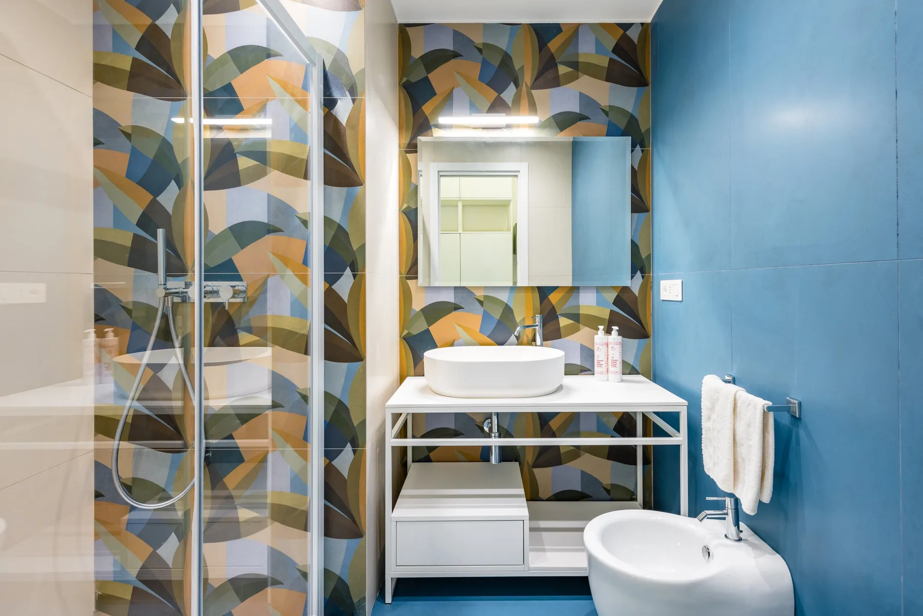 Un baño moderno con ducha de cristal, lavabo y paredes azules.