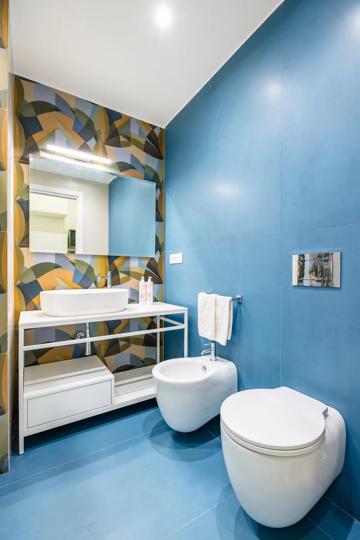 Un baño con lavabo, bidé e inodoro junto a paredes azules.