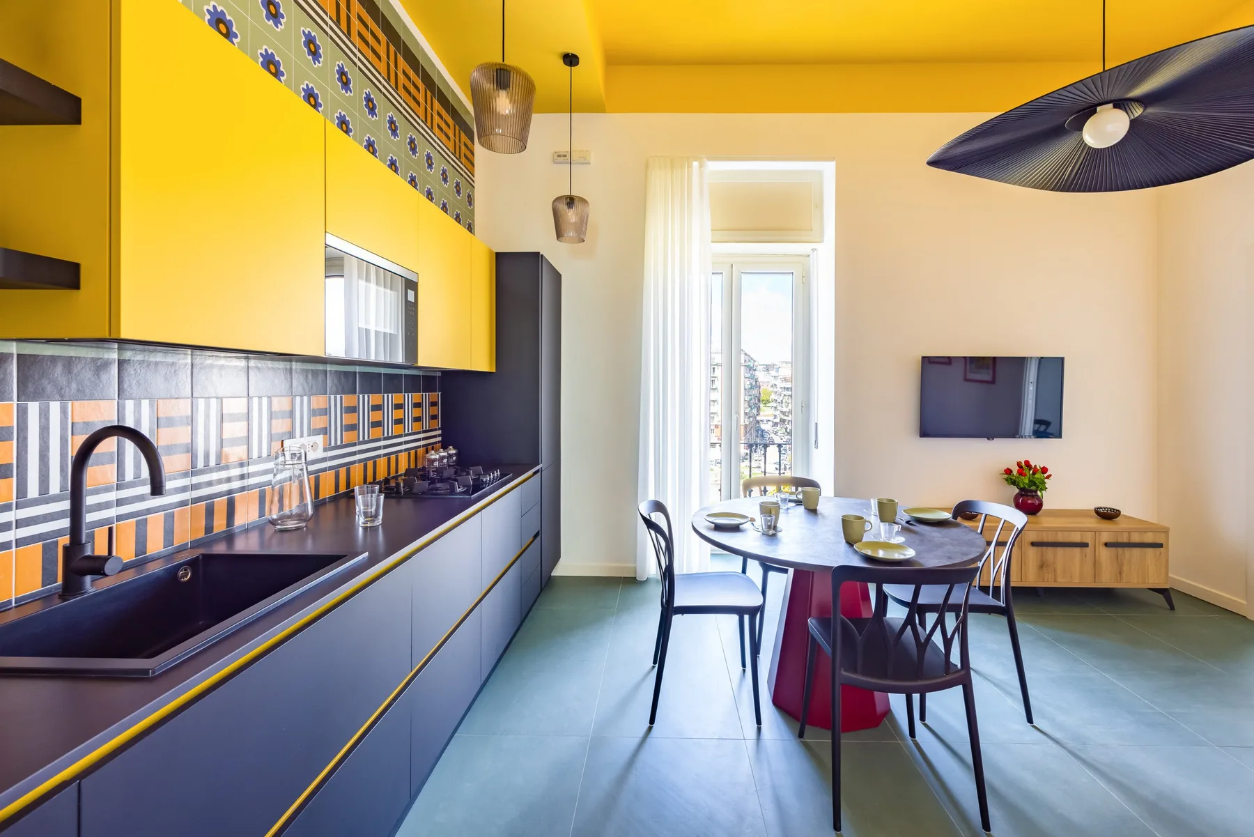 Una luminosa cocina con comedor, muebles amarillos y una mesa puesta.