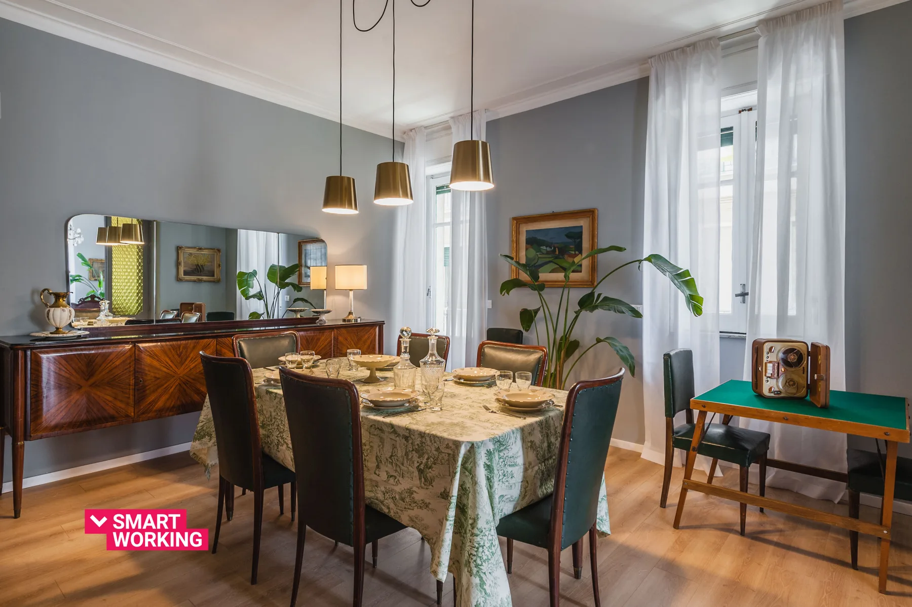 A dining room with a table set beneath pendant lights and a large mirror.