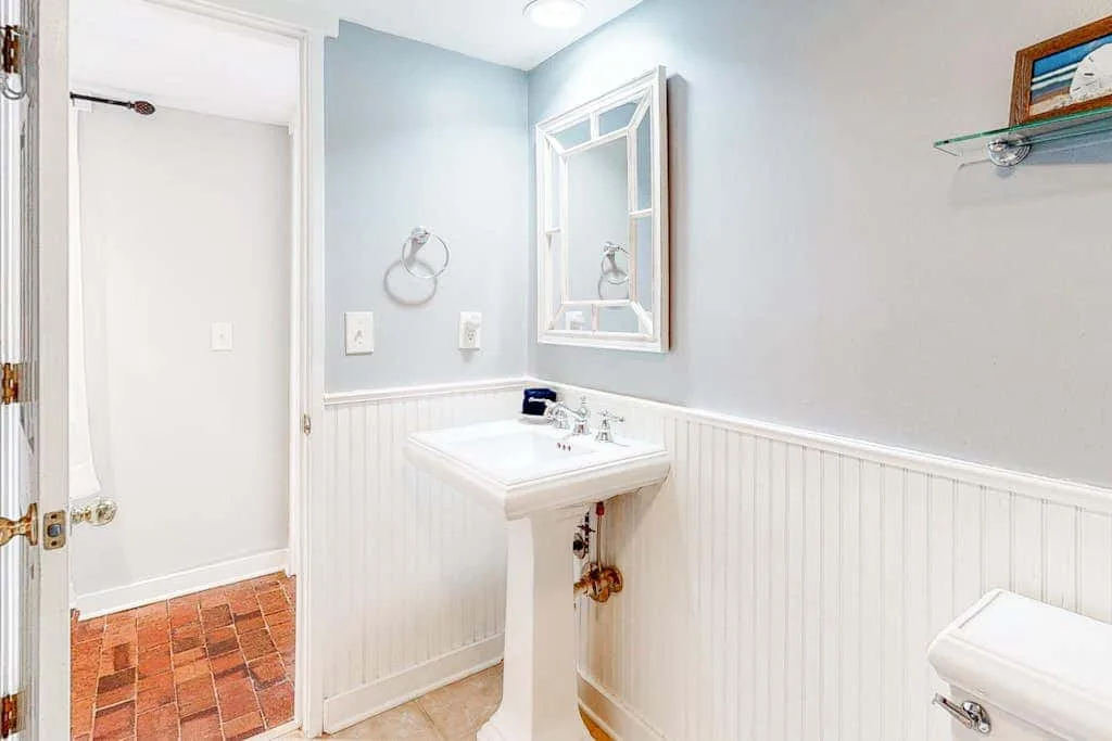 A bathroom with a pedestal sink and mirror.