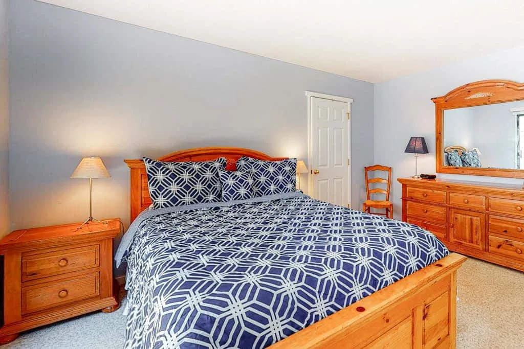 A bedroom with a wooden bed dressed in blue patterned bedding.