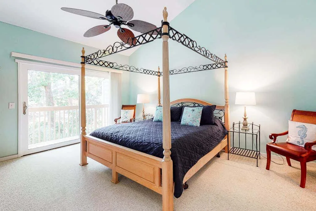 A bedroom with a canopy bed and glass doors opening onto a balcony.