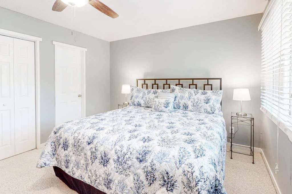 A bedroom with a bed covered in blue-and-white floral bedding.