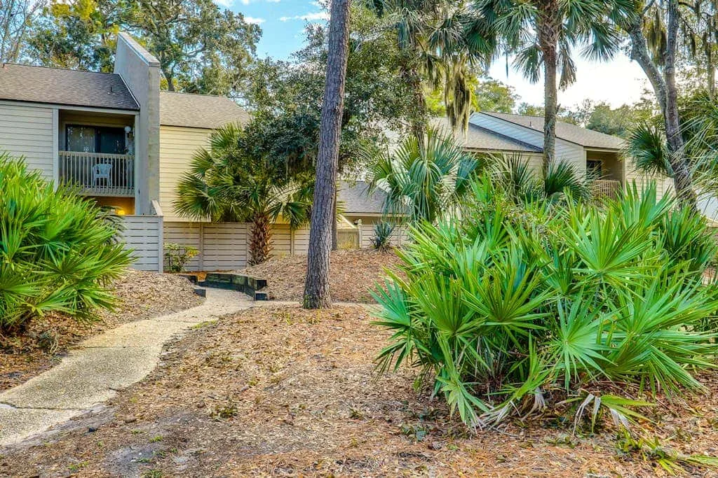 A low-rise building sits among palm trees and dense green shrubs.
