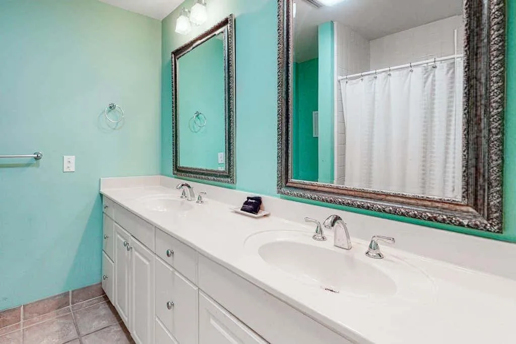 A bathroom vanity with a long white counter, two sinks, and wall mirrors.