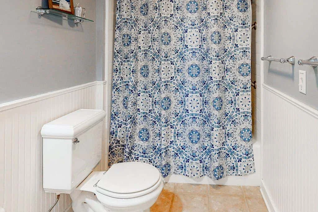 A bathroom with a toilet and a blue patterned shower curtain.