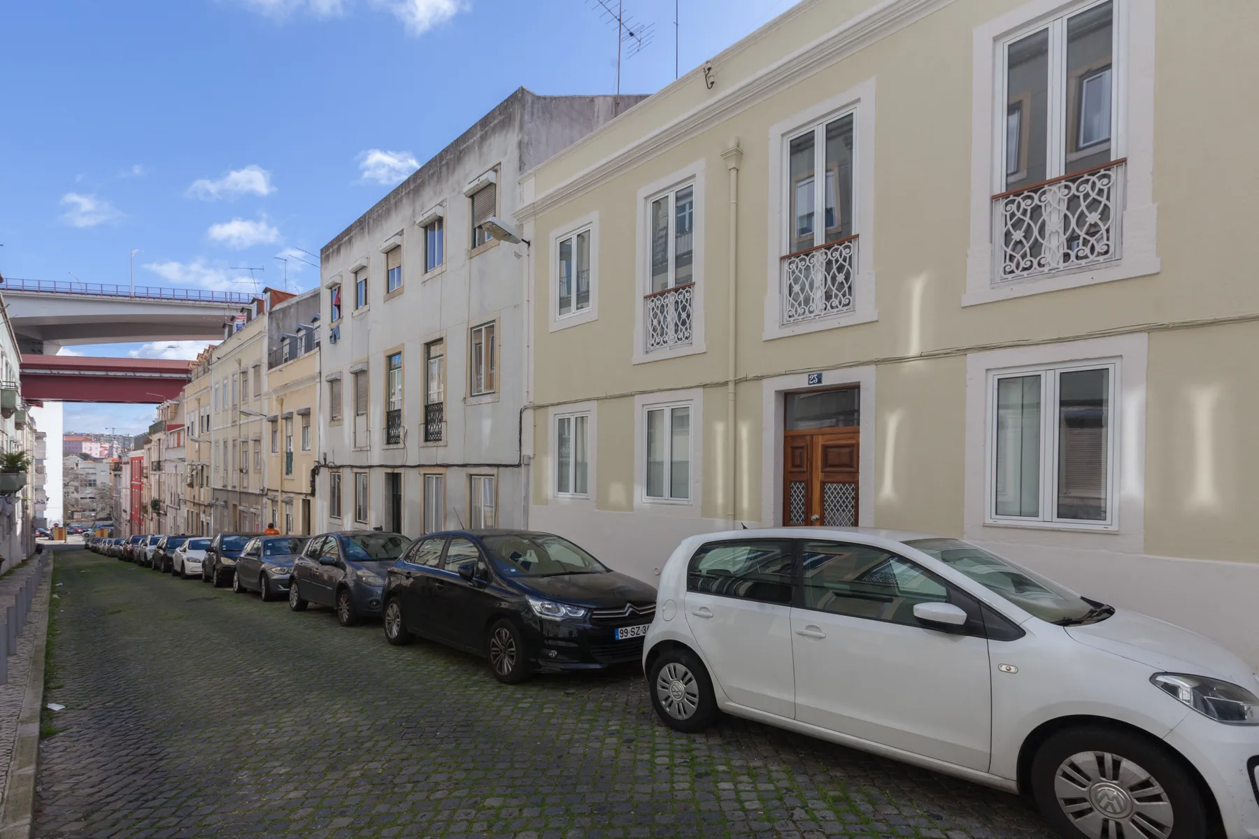 Una calle adoquinada con coches estacionados y edificios contiguos.