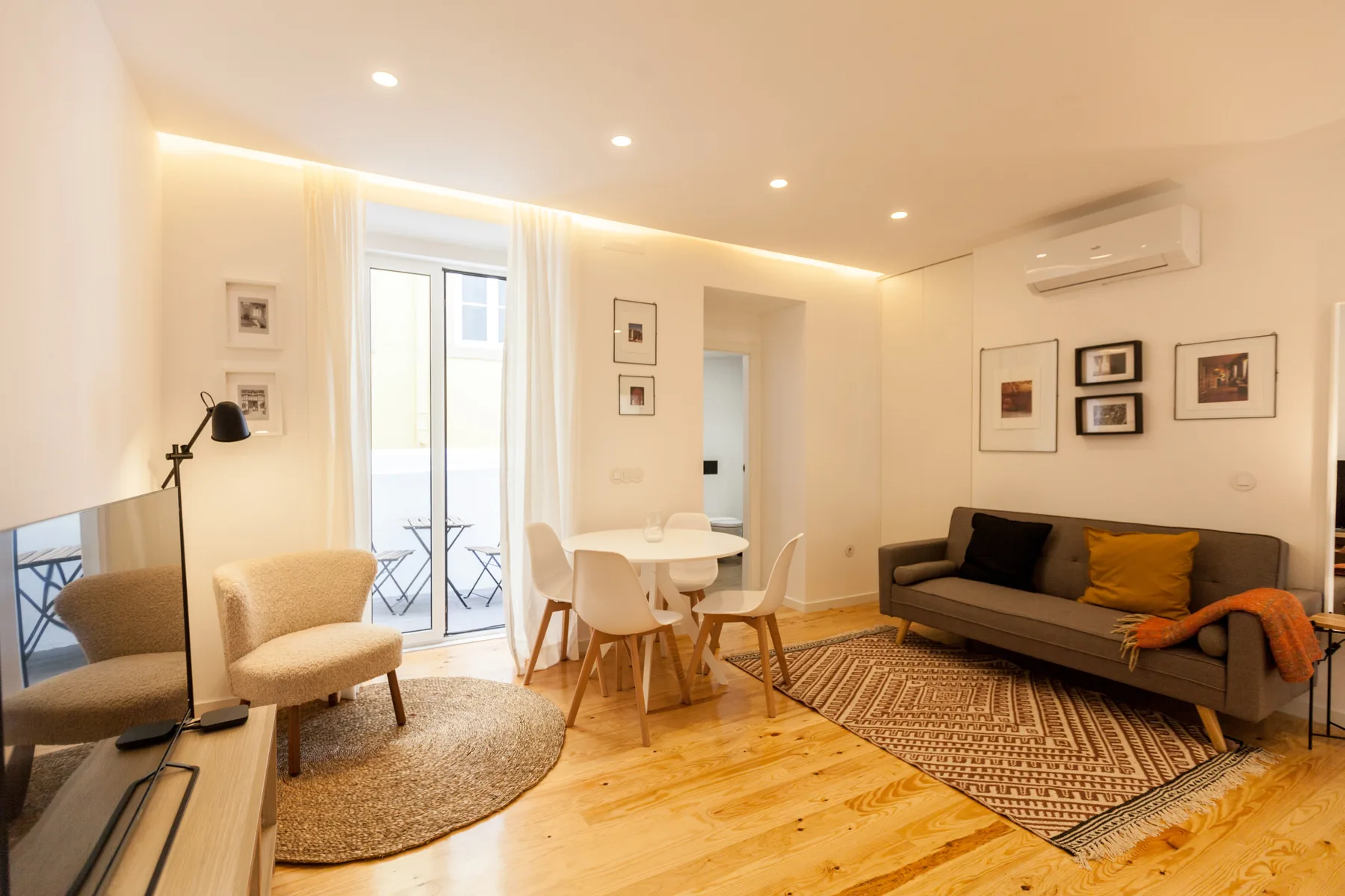 Una luminosa sala de estar y comedor con asientos, una mesa y puertas al balcón.