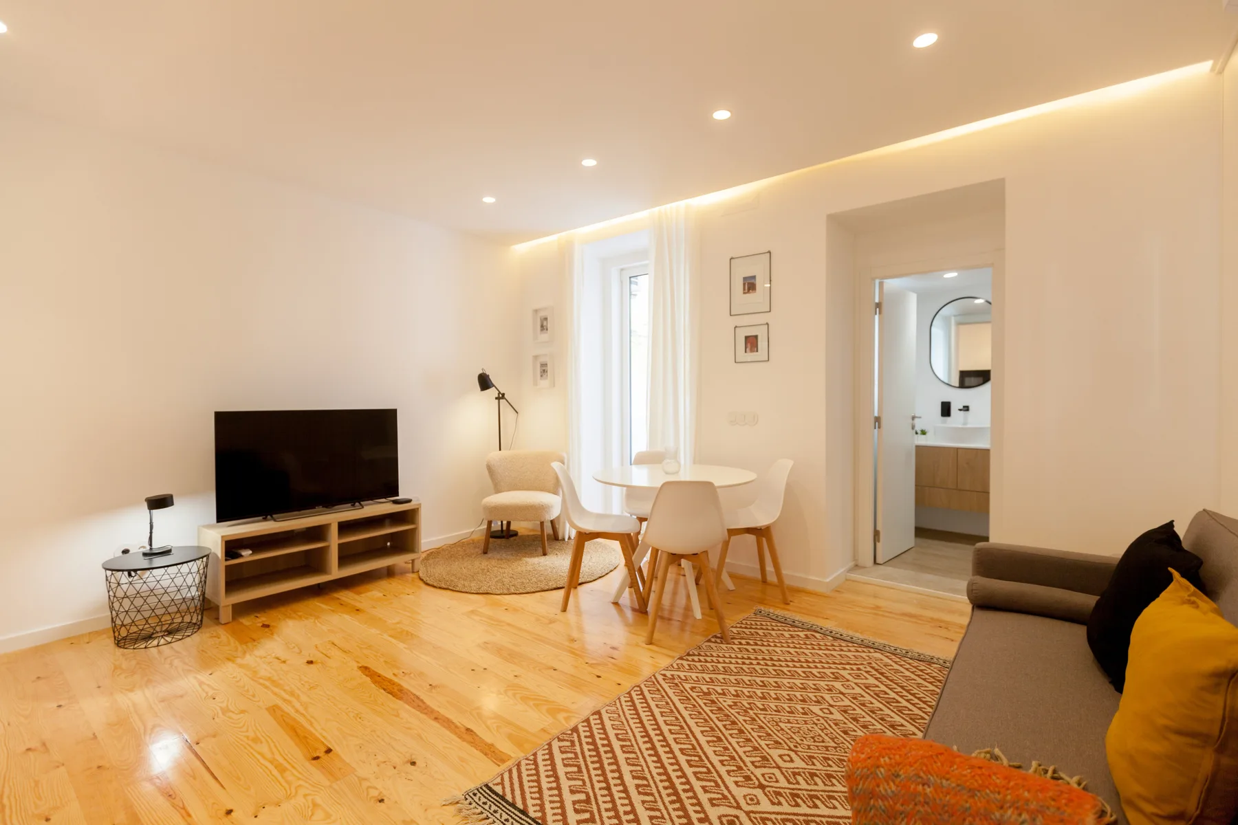 Una luminosa sala de estar y comedor con asientos, televisor y mesa.