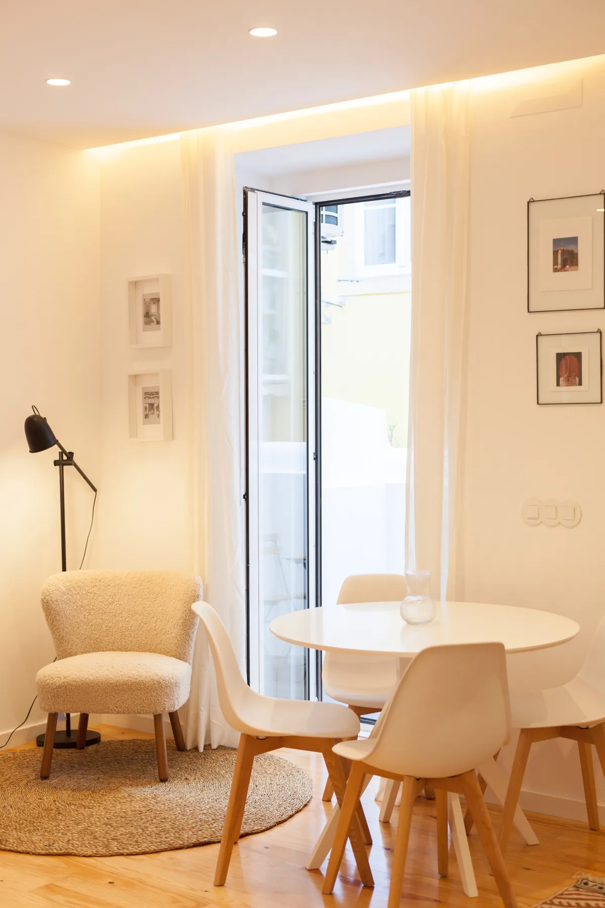 Un comedor luminoso con una mesa redonda y sillas junto a una puerta de vidrio abierta.