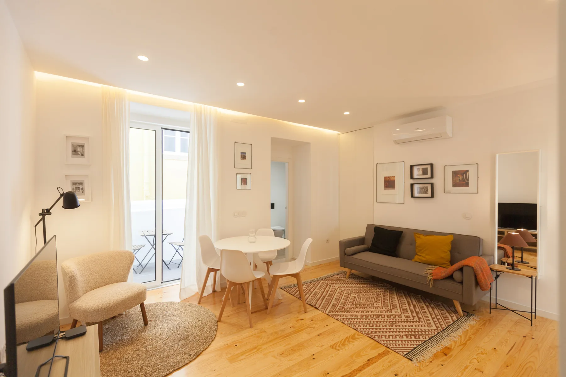 Una luminosa sala de estar y comedor con asientos, una mesa y una puerta al balcón.