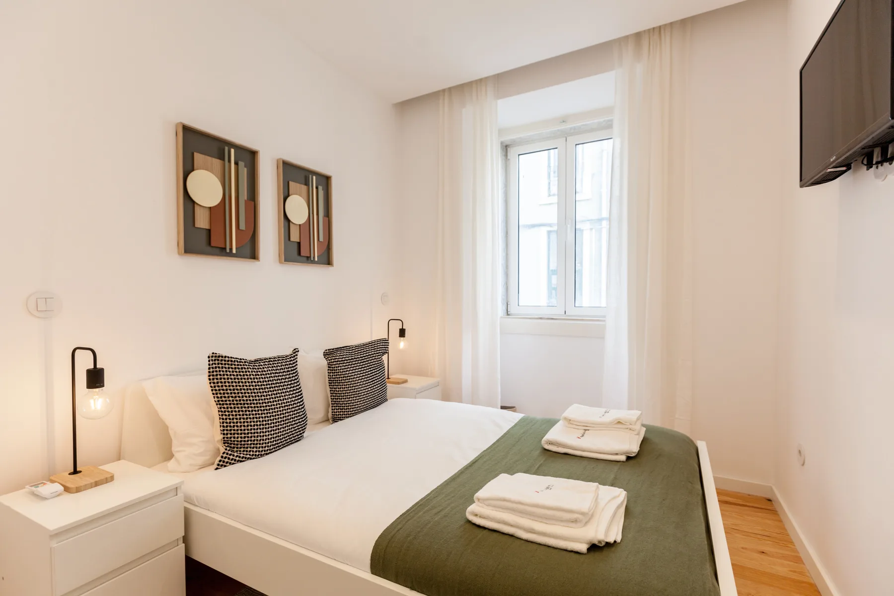 Un dormitorio con una cama bien hecha y una ventana.