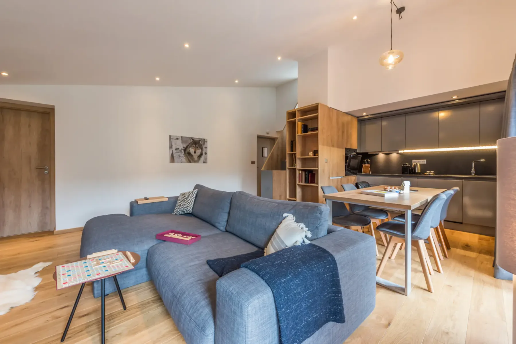 A living room with blue seating and an adjoining kitchen and dining area.