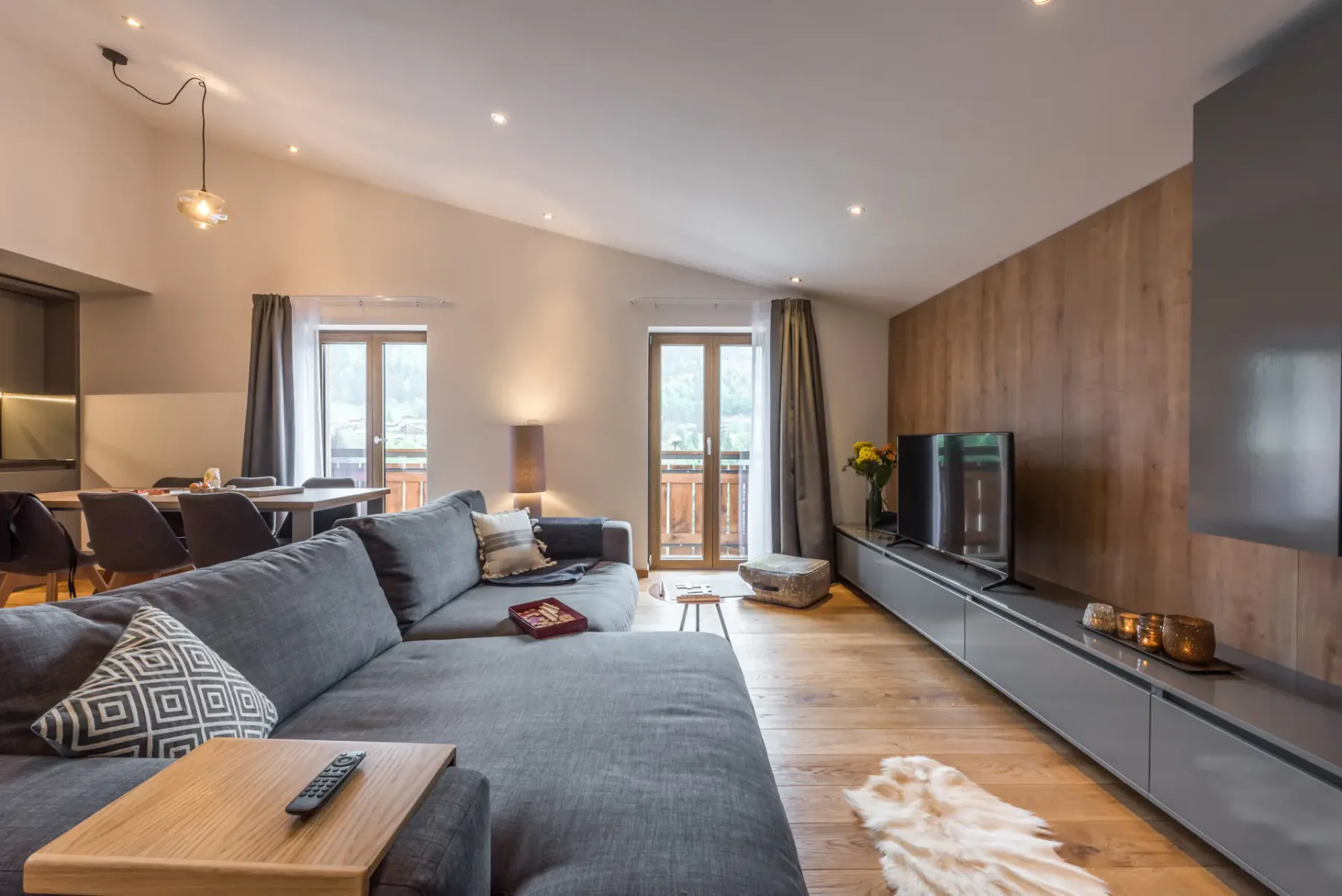 A living room with a sectional sofa, television, and wood-paneled wall.