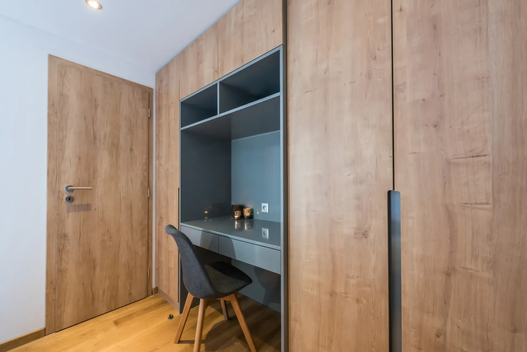 A bedroom workspace with a desk and chair built into wooden cabinetry.