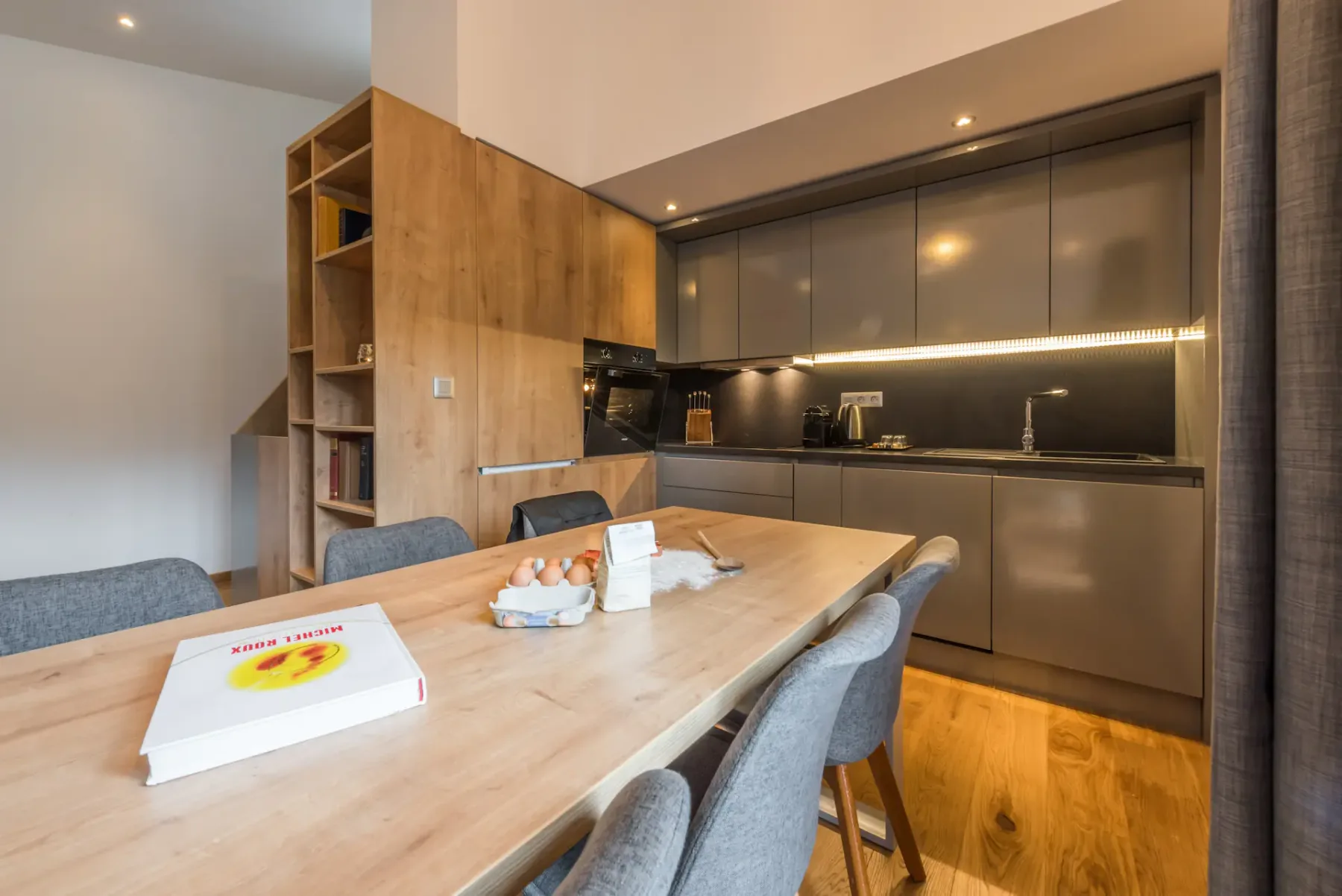 A contemporary kitchen with wood cabinetry and a dining table.