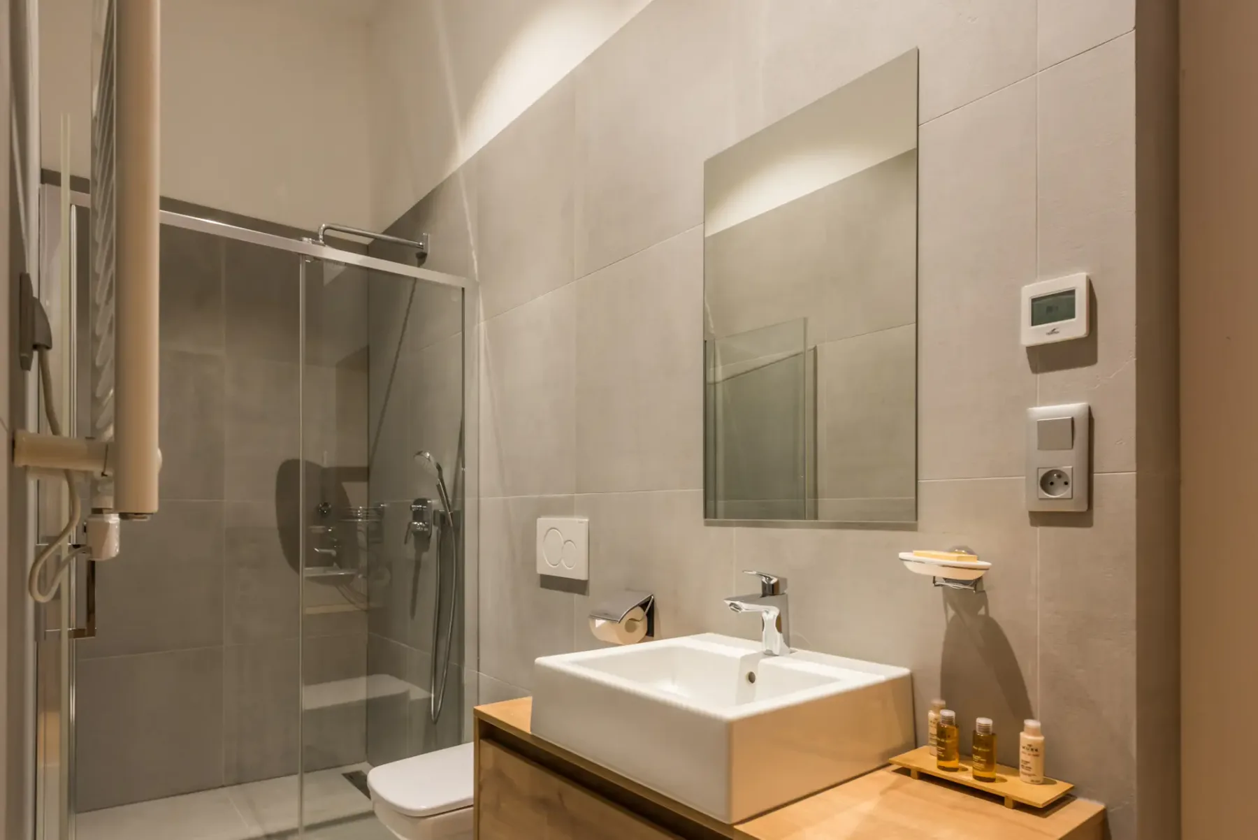 A tiled bathroom with a glass shower and a sink beneath a mirror.