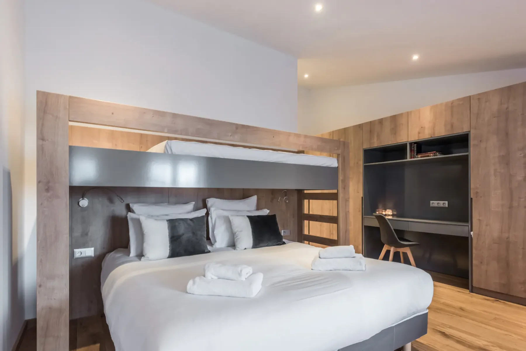 A bedroom with a large bed, white bedding, and built-in wooden storage.