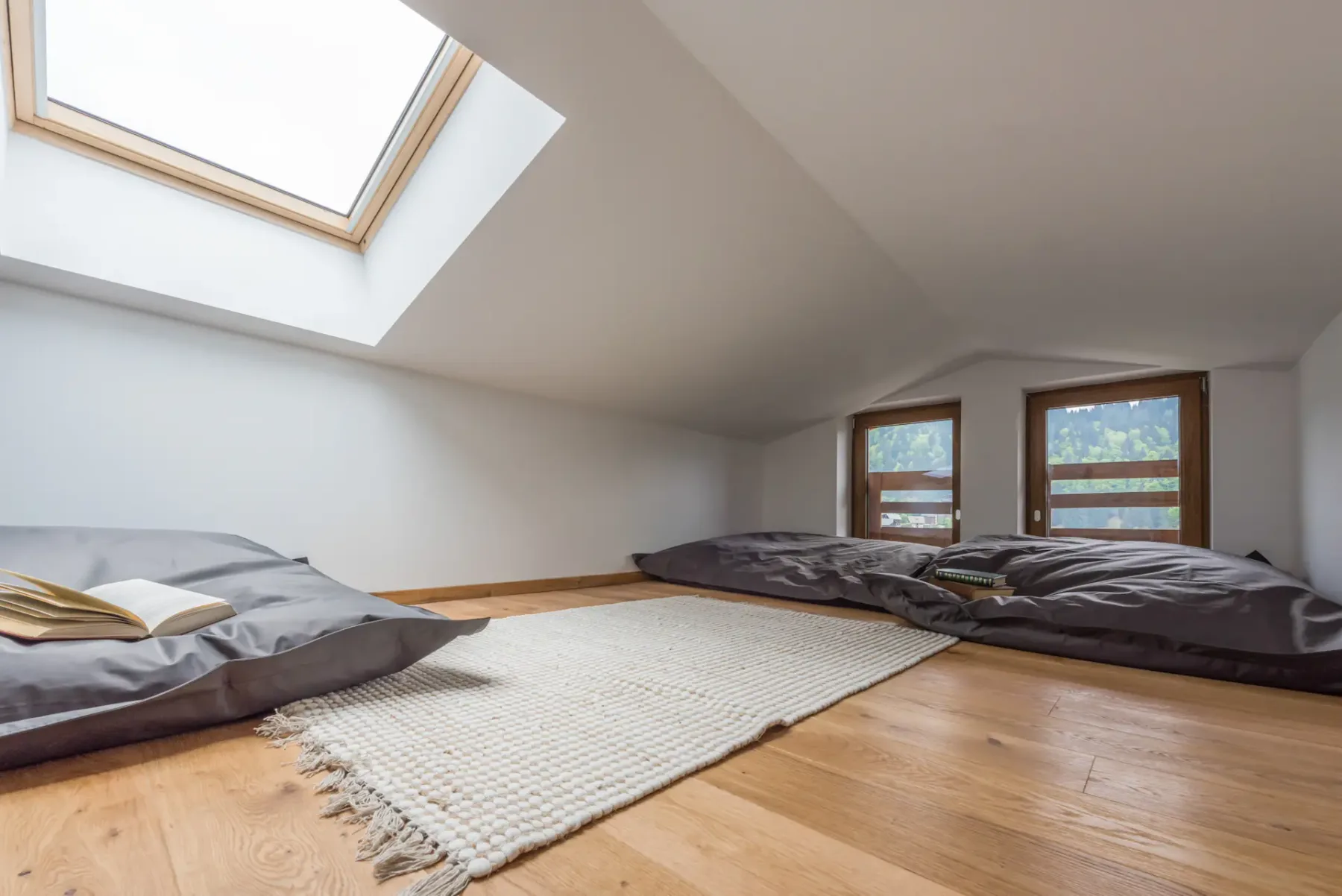 A bright attic bedroom with low beds arranged beneath a skylight.