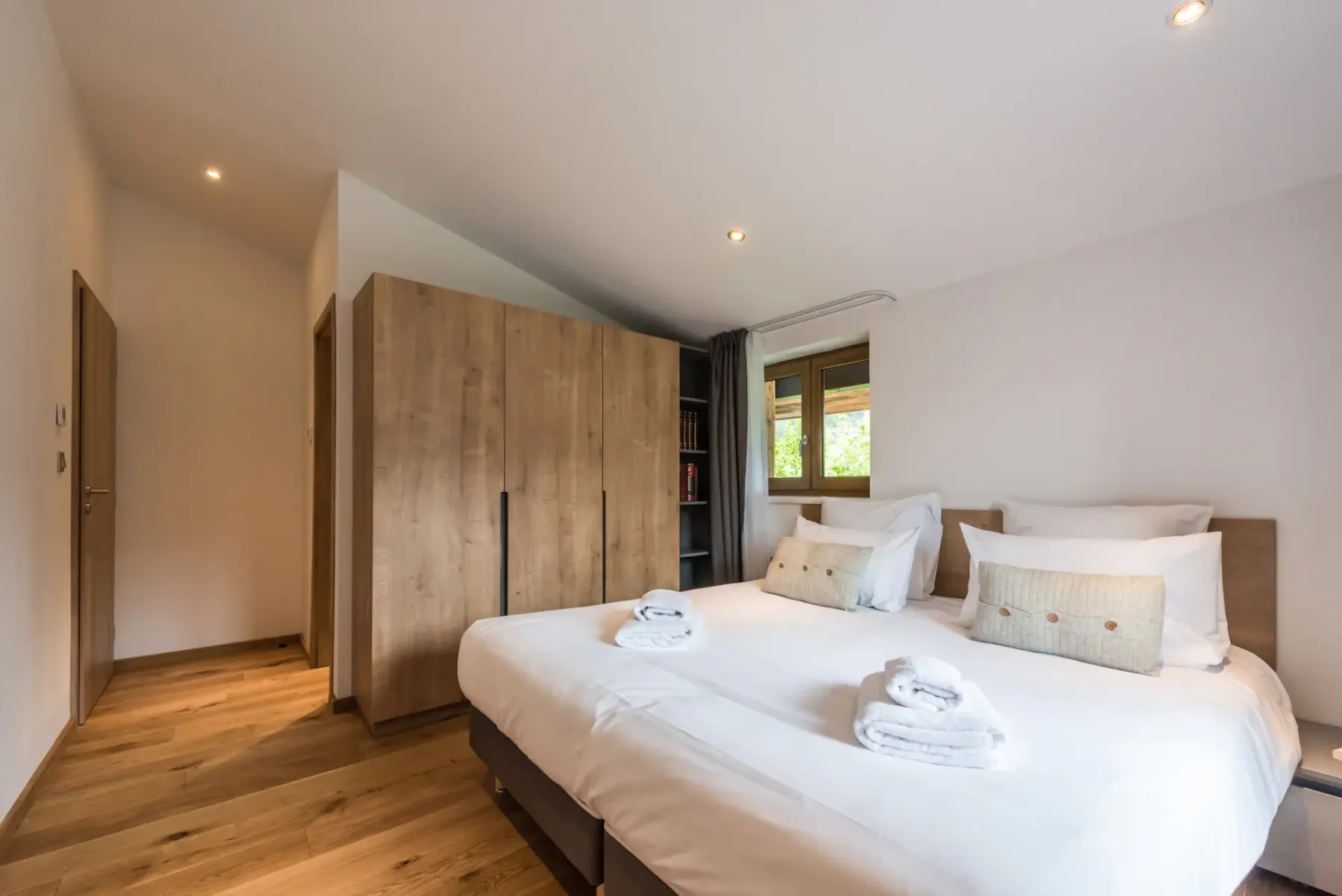 A bedroom with a neatly made bed and a wooden wardrobe.