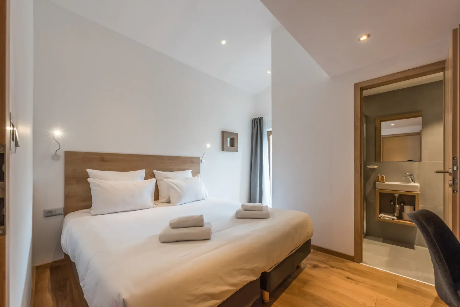 A bedroom with a made bed and an open doorway to a bathroom.
