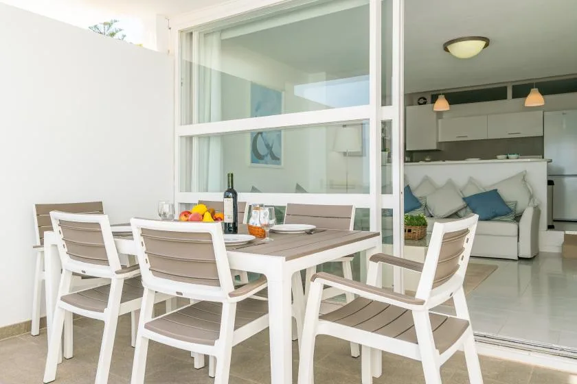 A patio dining area with a table and chairs beside a bright living room.