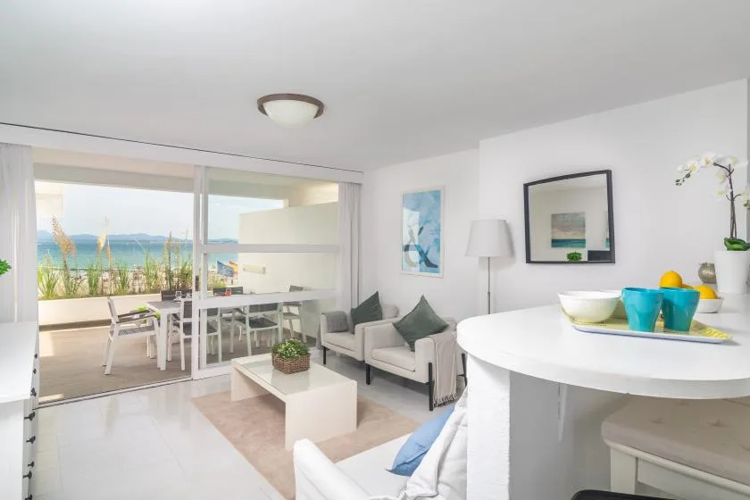 A bright living area with seating, a round table, and sliding glass doors opening to a balcony.