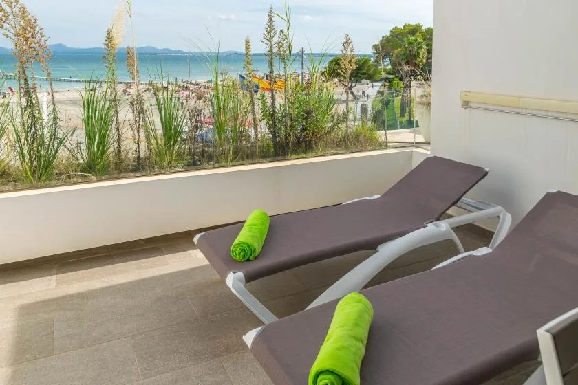 A seaside terrace has reclining loungers beside a view of the beach and ocean.