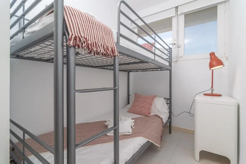 A bunk-bed sleeping area with striped bedding and a small bedside lamp.