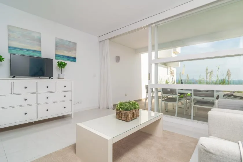 A bright living room with a coffee table, television, and sliding glass doors.